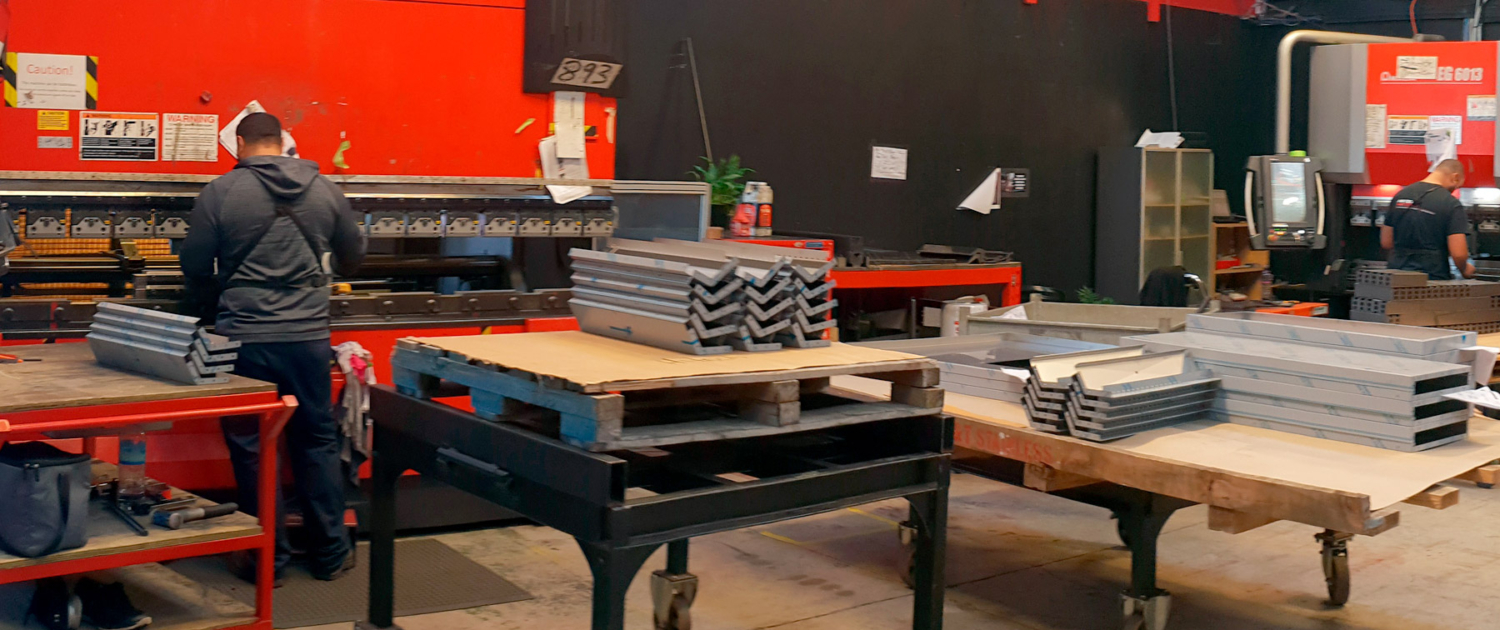 Image showing workers inside the Hi-Tech Metals premises using folding and pressing machinery.